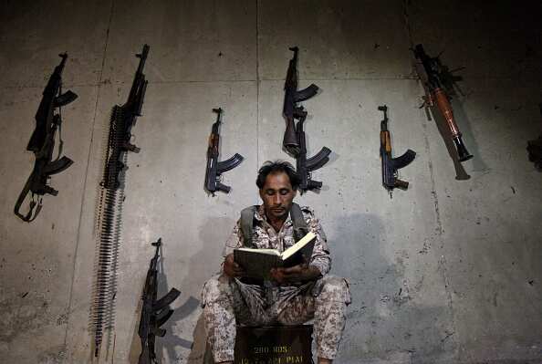 A Syrian rebel fighter reads the Koran as he sits in a fortified position.