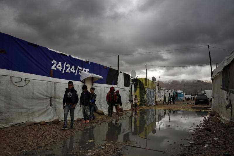 Syrian refugee children walk in mud after a heavy rain at a refugee camp in the town of Bar Elias, in Lebanon.