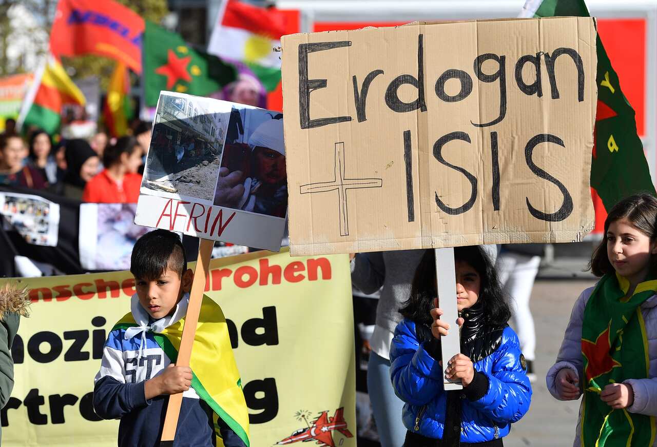 Children hold placards denouncing Turkey and the Turkish offensive in Germany. 