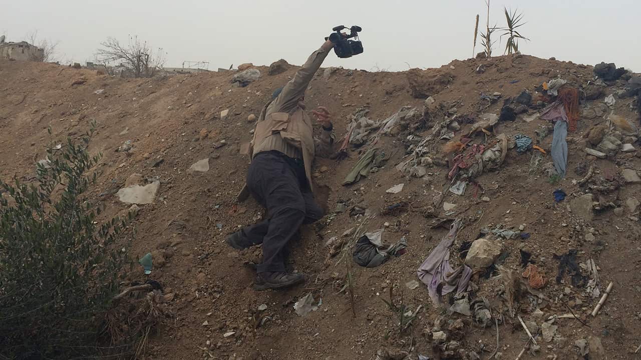 Luke raises his camera above the frontline to get a glimpse of rebel-held territory in Jobar, east of Damascus.