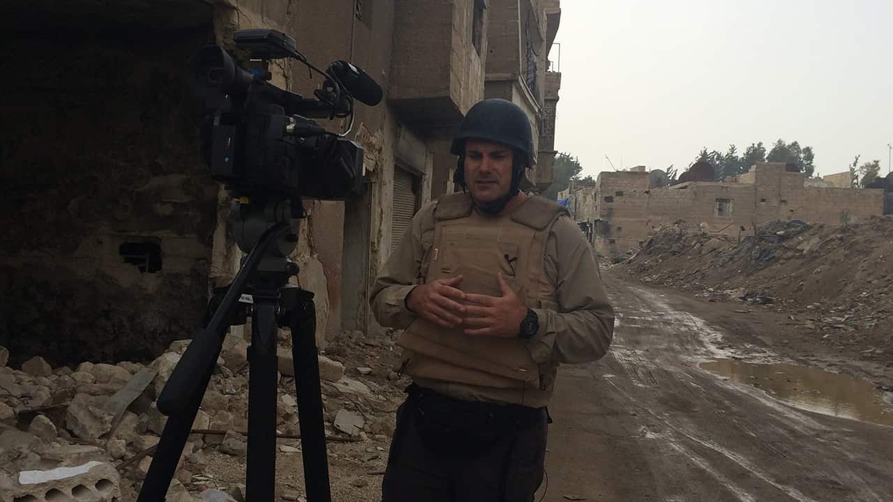 Luke wears protective clothing while filming in the damaged streets of Syria.