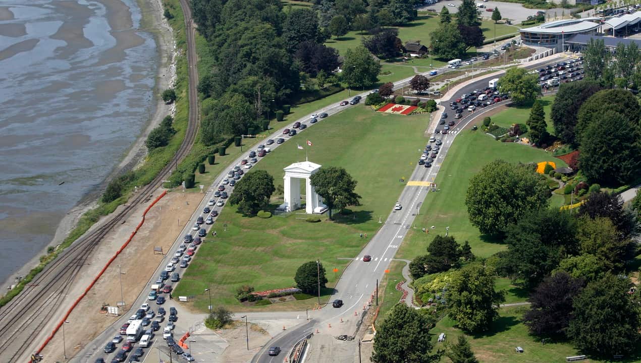 Cars line-up heading into the United States at left and into Canada at right adjacent to Boundary Bay at a border crossing at Blaine.
