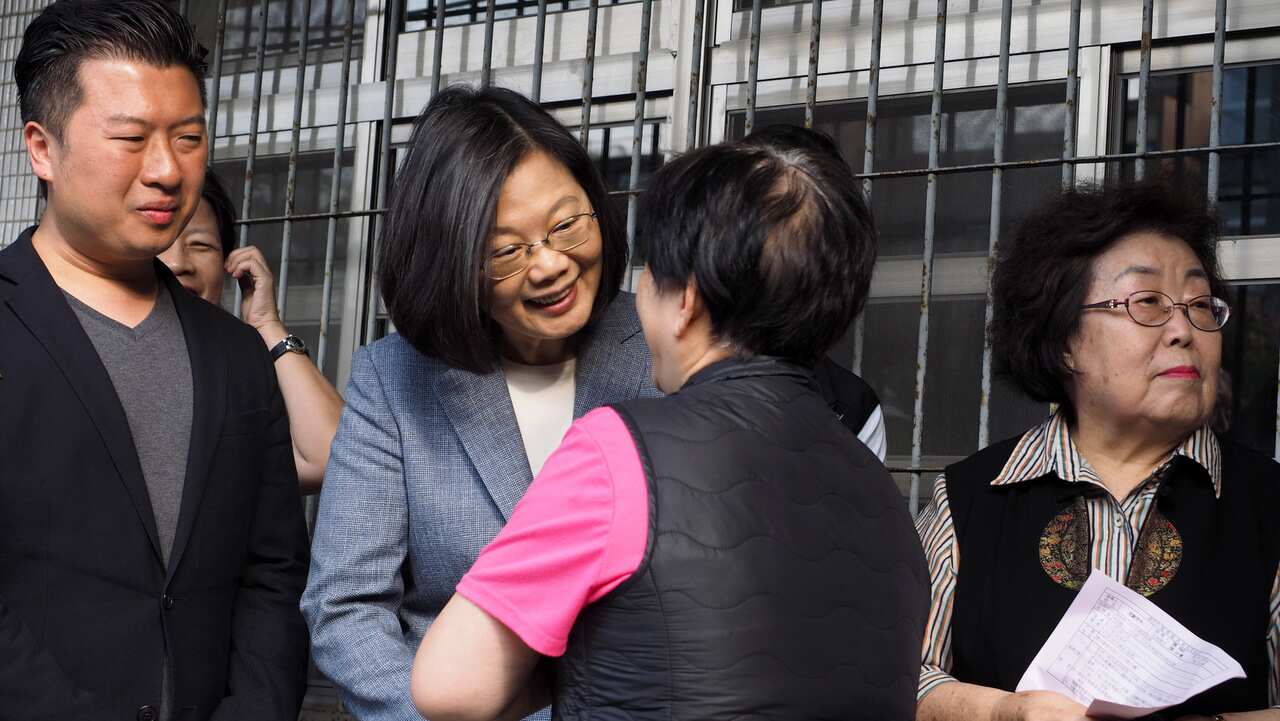 President Tsai Ing-wen chats with a woman while waiting to vote in local elections and referendums in Taipei.