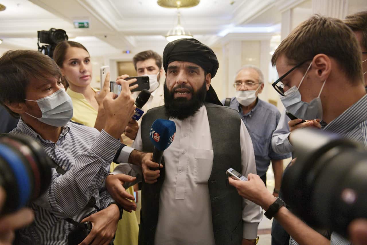 A man standing in a hallway surrounded by journalists