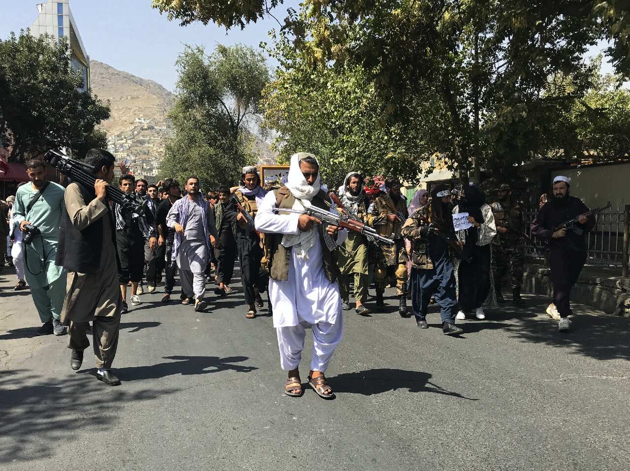 Taliban soldiers walk towards Afghans protesting in Kabul.