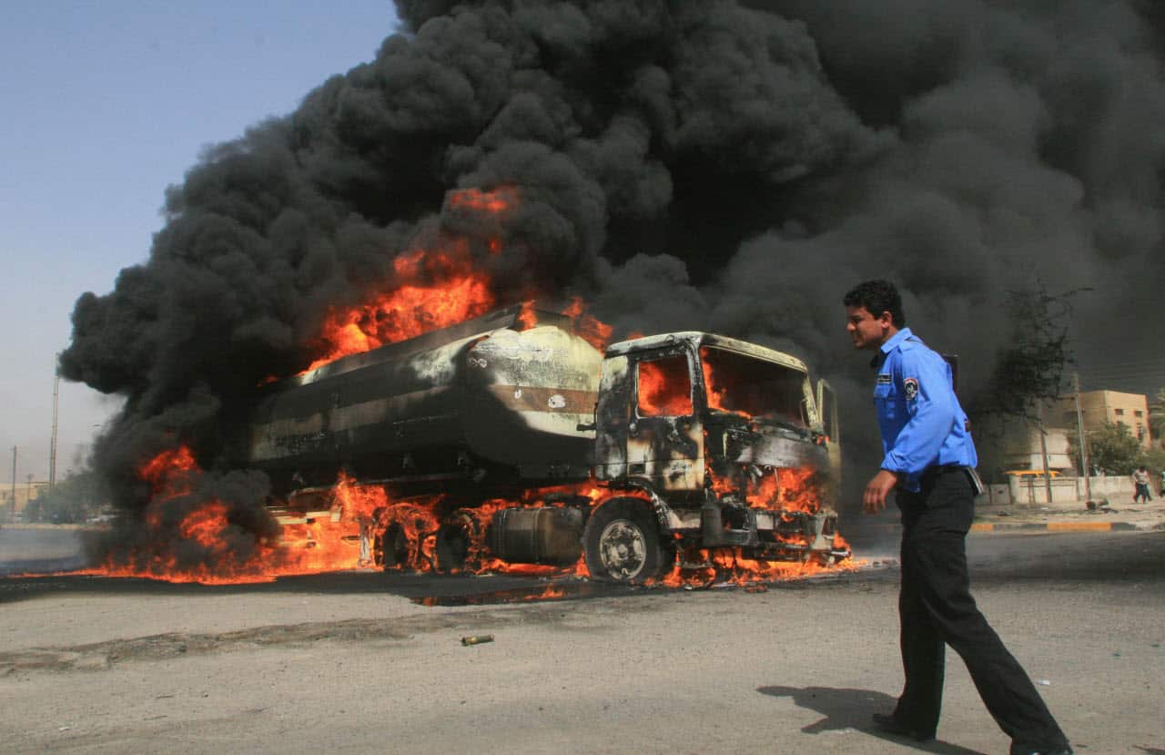 An Iraqi policeman walks past a burning fuel tanker in the Iraqi southern city of Basra, May 21 2007 after the British military supply convoy was attacked. 