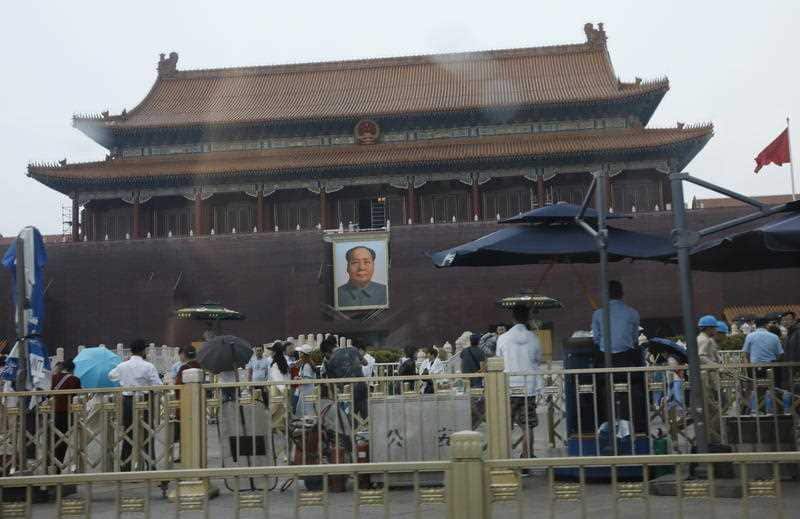 Police officers stand guard under umbrellas as visitors throng Tiananmen Square on the 30th anniversary of the 1989 Tiananmen Square protests in Beijing.