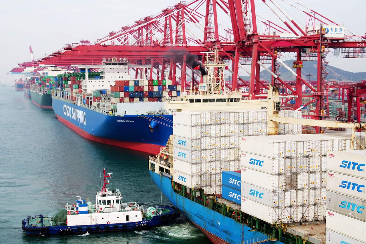 A barge pushes a container ship to the dockyard in Qingdao in eastern China's Shandong province.