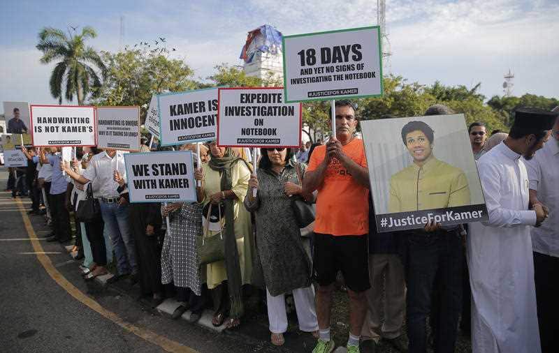 Family members, human rights activists and civic groups hold placards and photographs of Kamer Nizamdee.