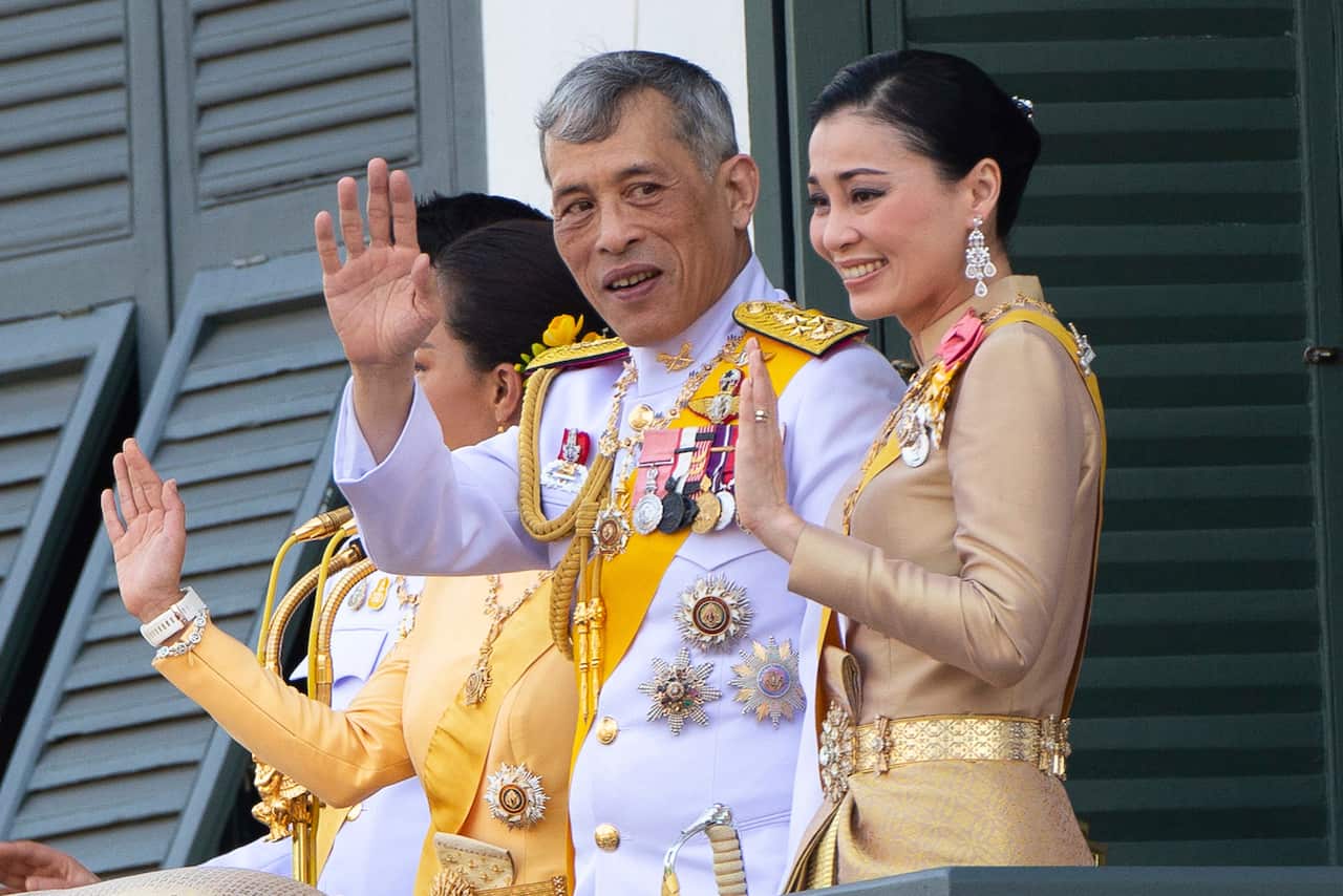 King Vajiralongkorn and Queen Suthida wave to an audience from the balcony of Suddhaisavarya Prasad Hall during their coronation ceremony.