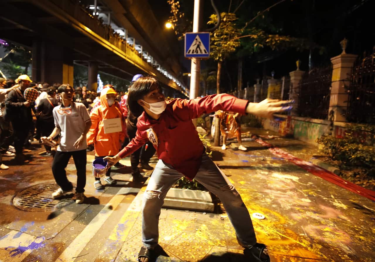 A pro-democracy protester throws a bucket of paint over the gate of the Thai police headquarters during a protest calling for political and monarchy reform.