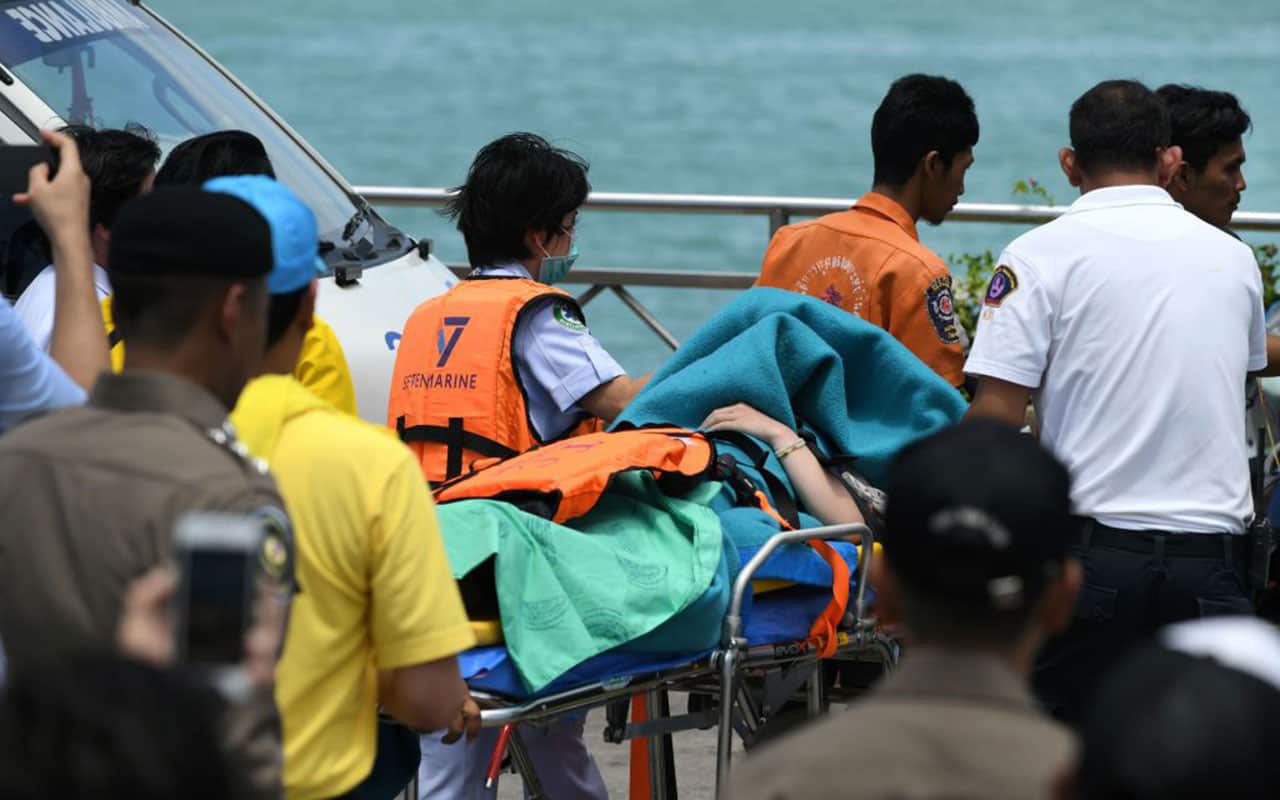 Thai emergency personnel transfer a passenger (C) from the sunken tourist boat at the Chalong pier in Phuket on July 6, 2018.