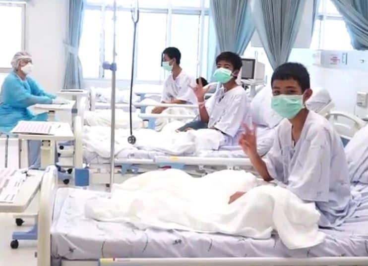 The boys smile and wave while recovering in hospital.