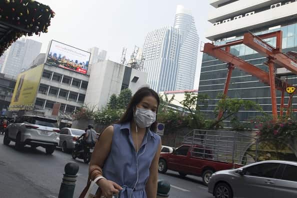 A woman wears a face mask on the way to work while smog blankets Bangkok.