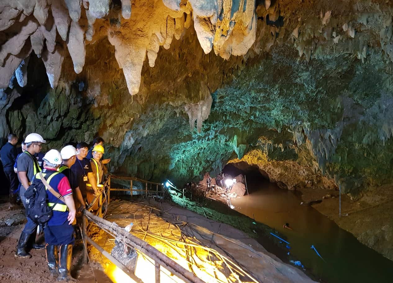 Thai workers and associated officials watch to the flooded cave as they attempts to drain the water from the cave 