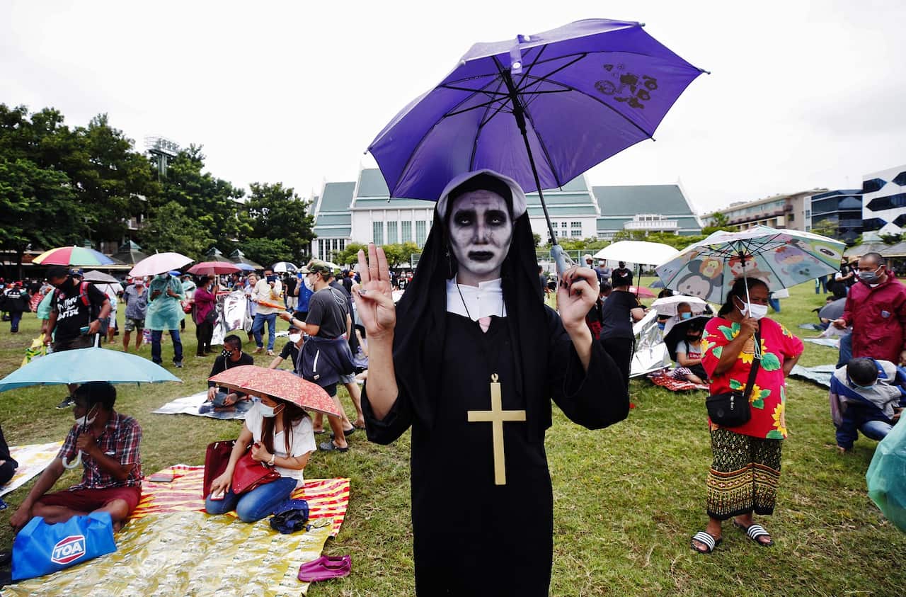 A pro-democracy protester dressed in a zombie nun costume performs the three-finger salute at Thammasat University during a protest in Bangkok.