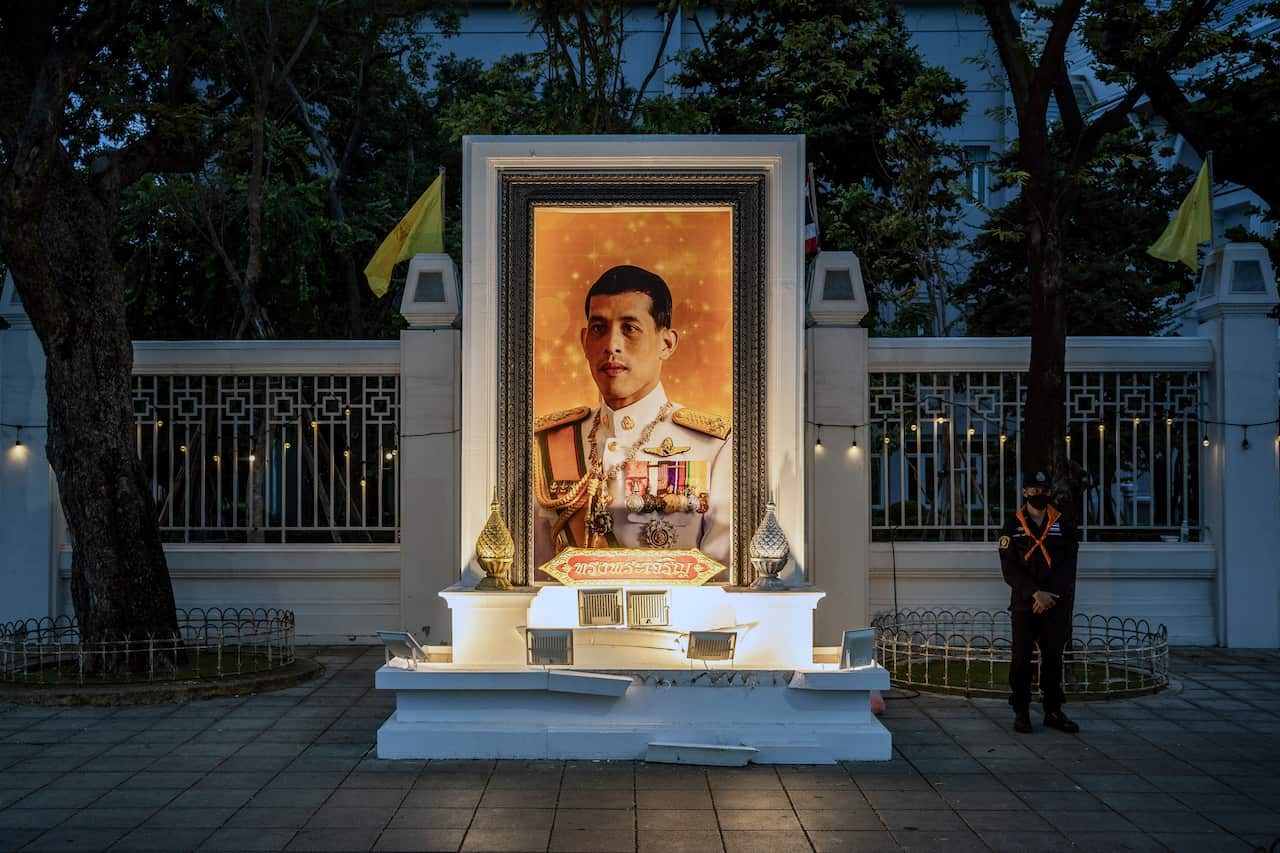 A police officer stands guard next to a portrait of King Maha Vajiralongkorn Bodindradebayavarangkun during protests in Bangkok on Sept. 20, 2020.  
