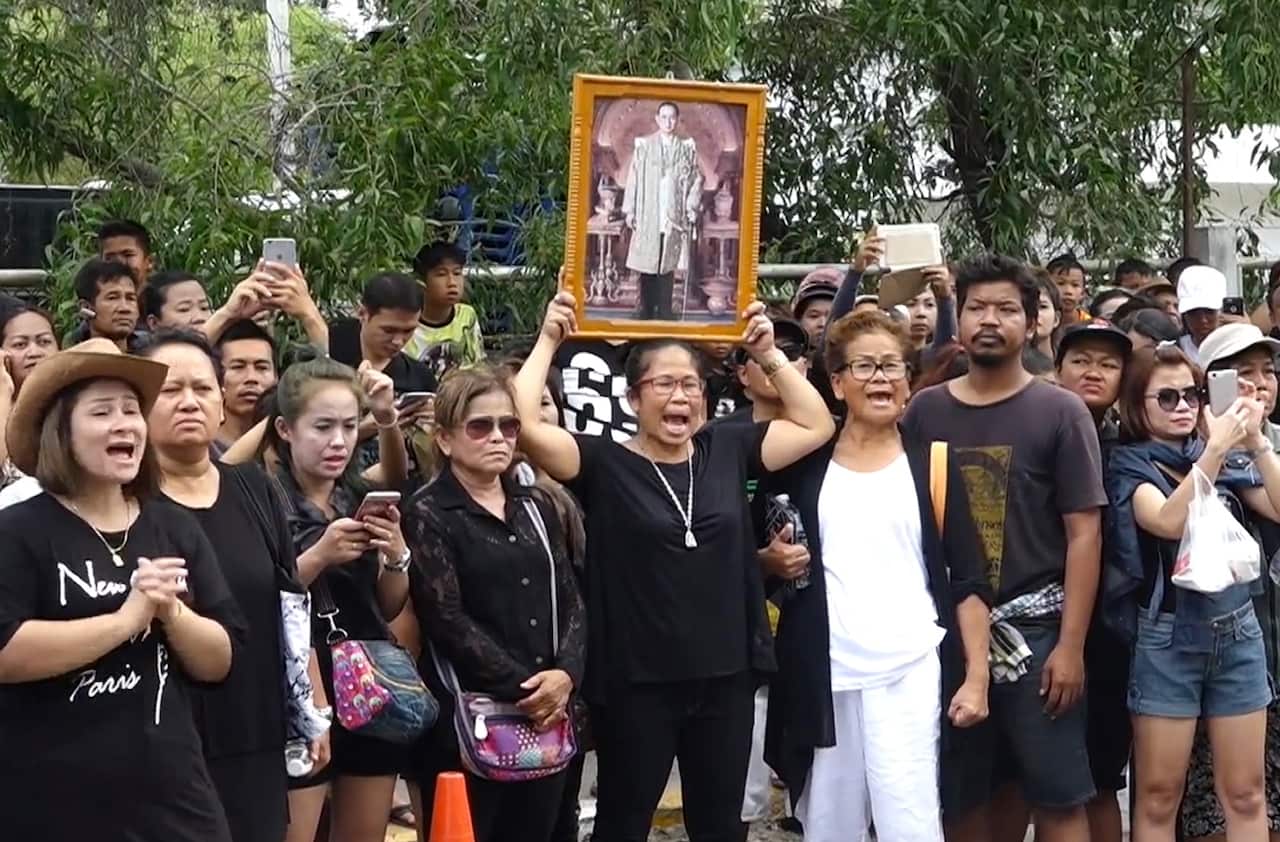 A crowd publicly shame Umaporn Sarasat as she arrives at a police station to face charges of insulting the monarchy (AAP)