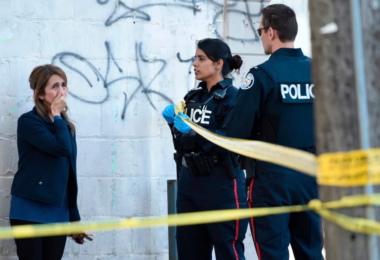 Toronto police officers talk to a woman after a van mounted a sidewalk crashing into a crowd of pedestrians in Toronto on Monday, April 23, 2018.