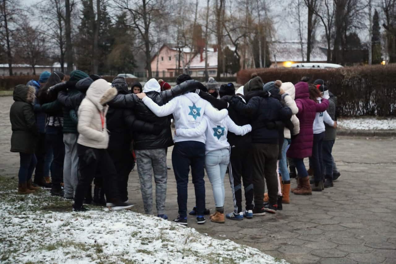 Israeli students huddle to sing their national anthem, Hatikvah, after visiting gas chamber and crematorium 1.