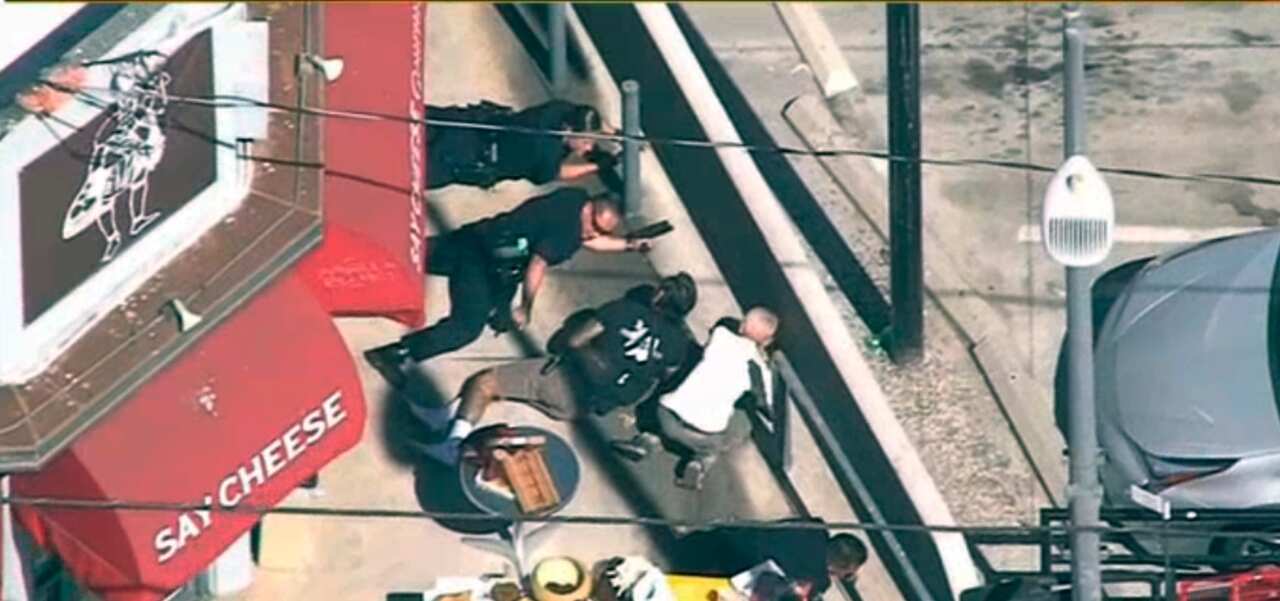 In this image from video provided by KNBC-TV, police and civilians take cover near a Trader Joe's supermarket in the Silver Lake district of Los Angeles