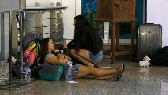 Passengers wait at the airport as flights are cancelled following the volcanic eruption of Mount Agung.