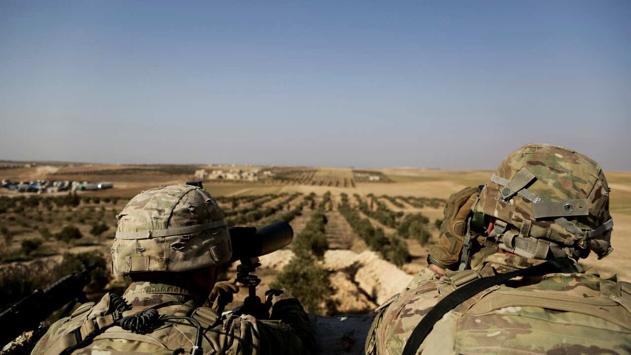 American troops look out toward the border with Turkey from a small outpost near the town of Manbij, northern Syria on February 7, 2018.