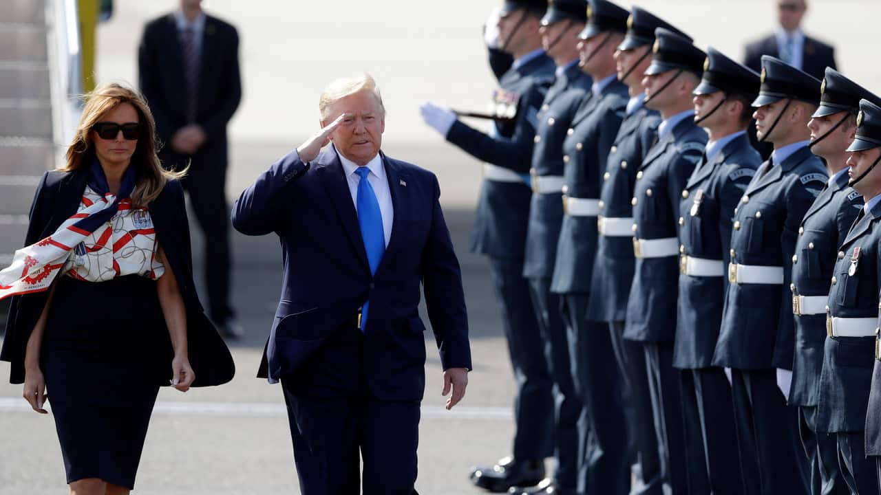 President Donald Trump salutes an honor guard as he and first lady Melania Trump arrive at Stansted Airport in England.