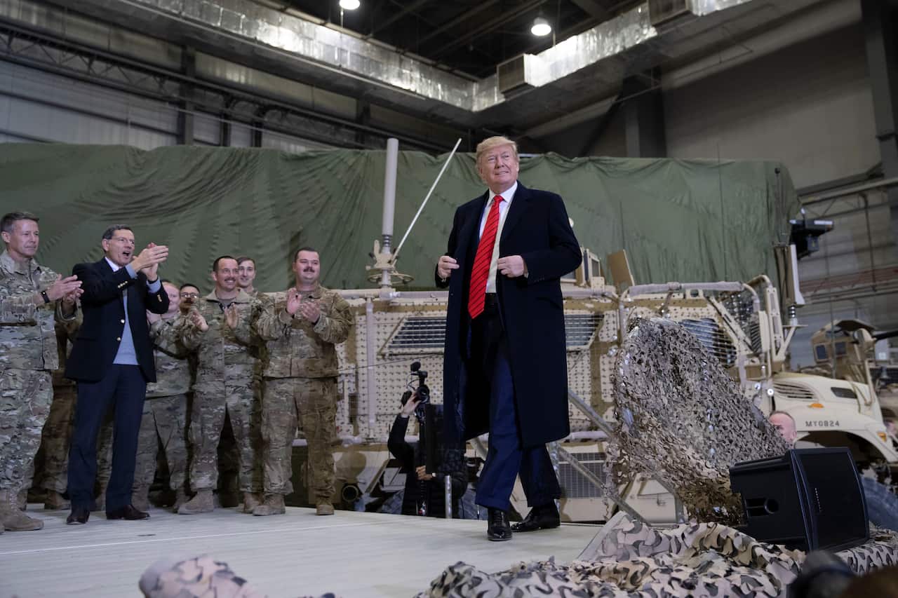 President Donald Trump walks on stage during to address members of the military during a surprise Thanksgiving Day visit.