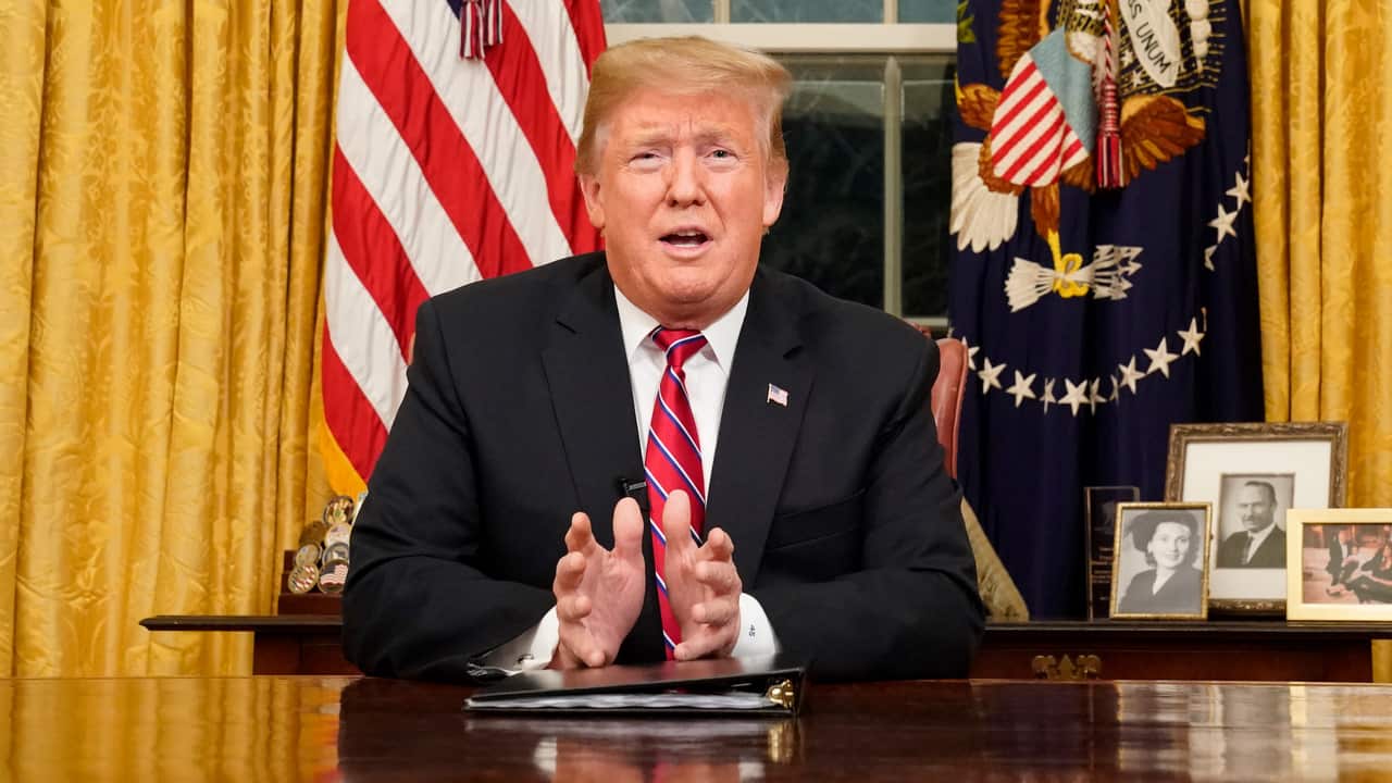 US President Donald Trump deliversa televised address to the nation from his desk in the Oval Office.
