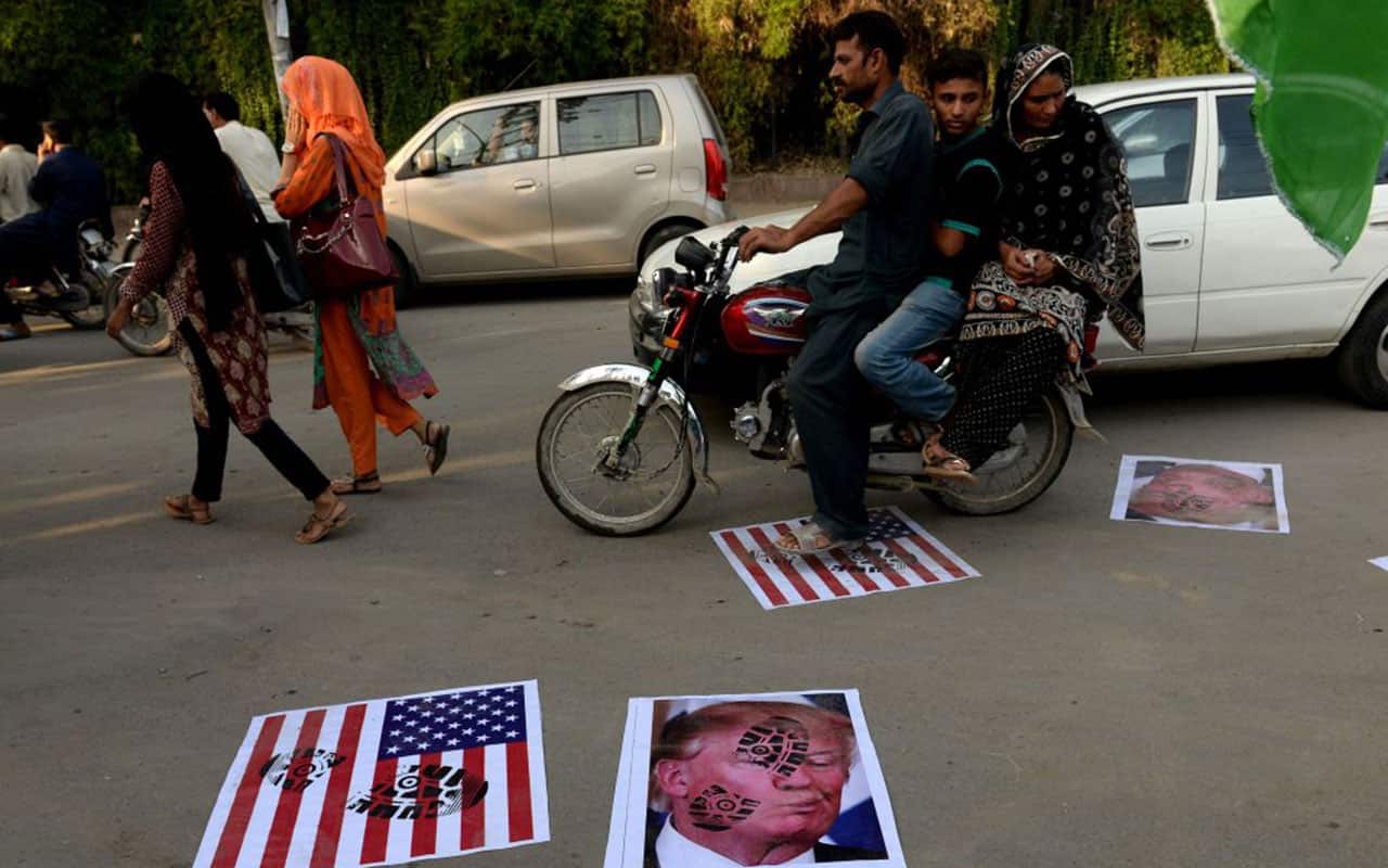 A Pakistani motorcyclist rides over images of US President Donald Trump and a US flag on a street in Lahore on August 25, 2017. 