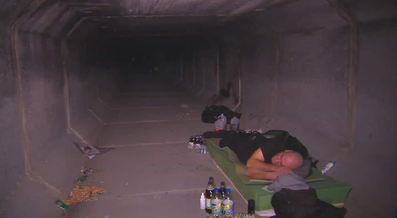A man sleeps in one of the drains