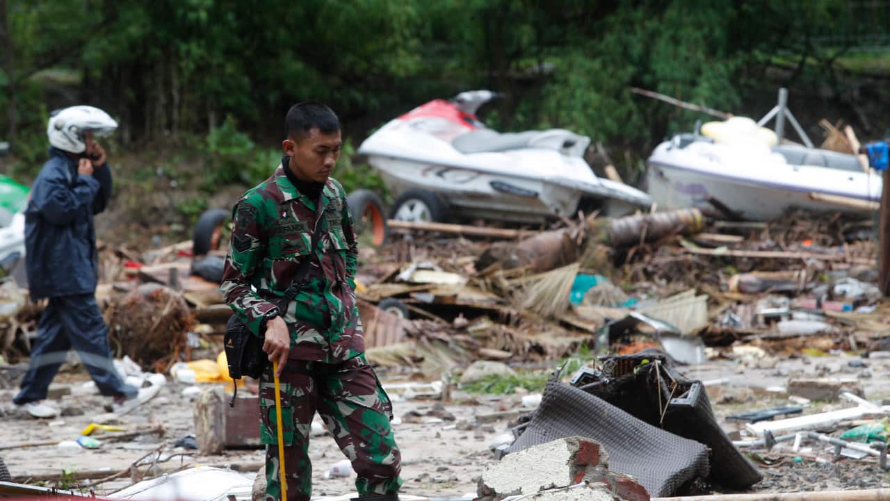 A rescuer walks among debris in a devastated area after a tsunami hit the Sunda Strait.