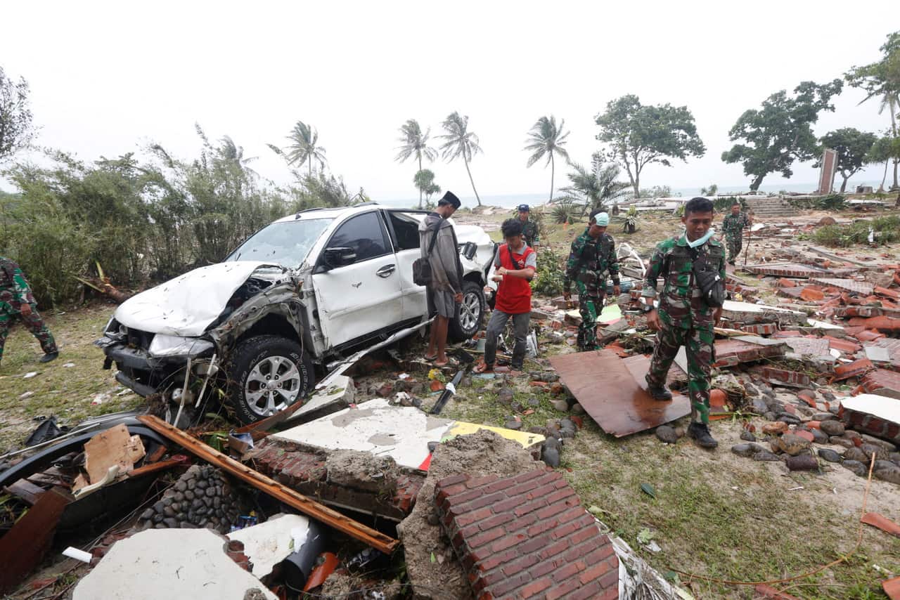 Rescuers walk among debris after a tsunami hit Sunda Strait, in Tanjung Lesung, Banten, Indonesia.