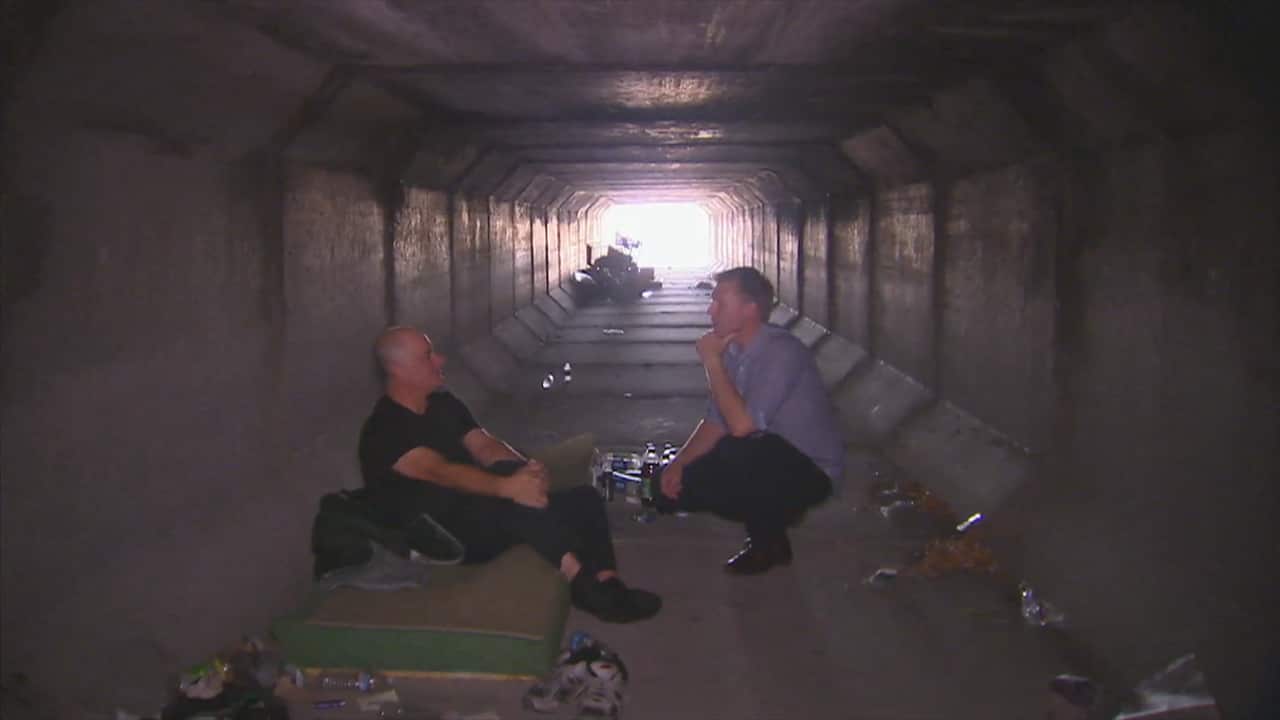 SBS reporter Brett Mason (right) speaking to a resident of the drains (SBS)