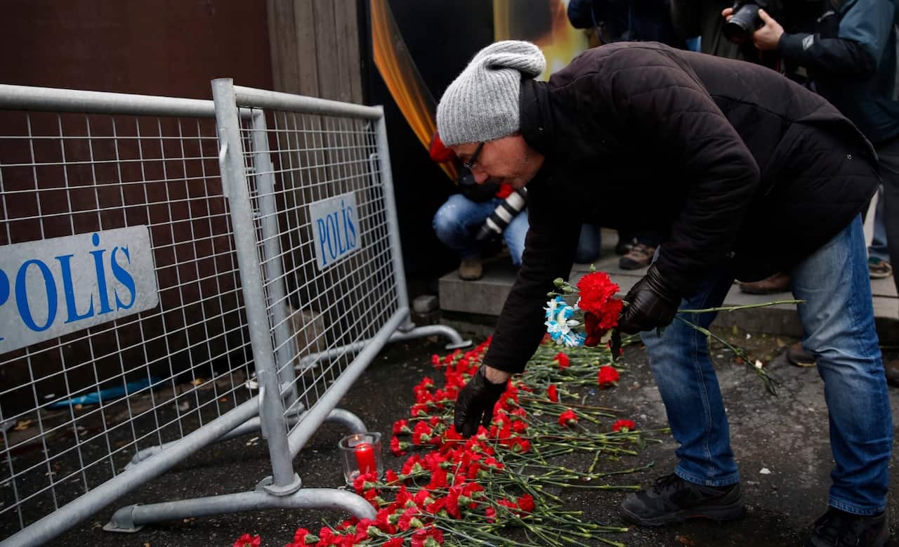People place flowers and candles at a police barrier in front of the Reina night club (AAP)
