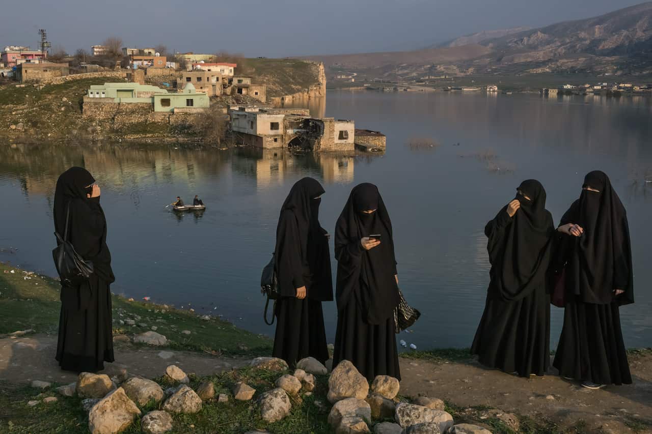Visitors walk along the bank of the Tigris River as its rising waters flood the old town of Hasankeyf, Turkey, Feb. 24, 2020.