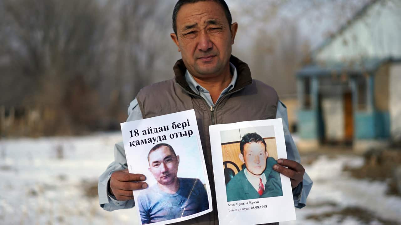 Adilgazy Yergazy, a farmer, holds up pictures of his detained little brothers at his home in a village near Almaty, Kazakhstan.  