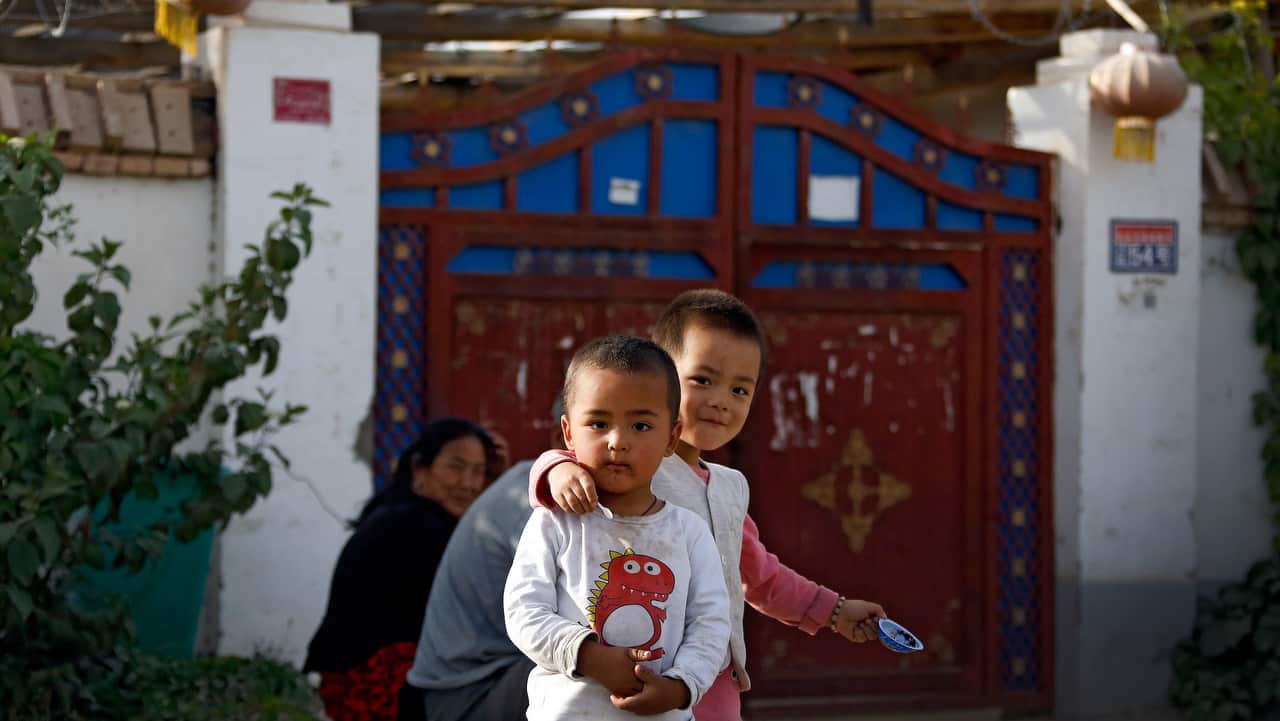 Uighur children play while their relatives rest outside their house at the Unity New Village in Hotan, in western China's Xinjiang region.