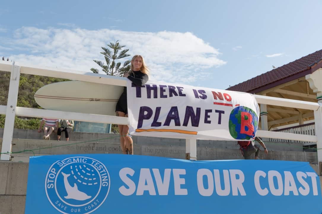 Photo of surfer alongside Save Our Coast protest banner.