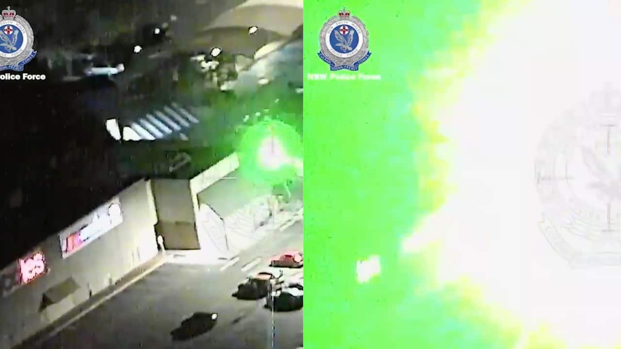 A man with a laser beam shines the powerful light towards a NSW Police chopper. 