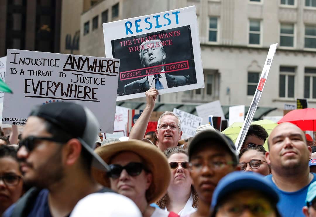 A man holds a sign reading "Resist" at a demonstration against Donald Trump's immigration policies.