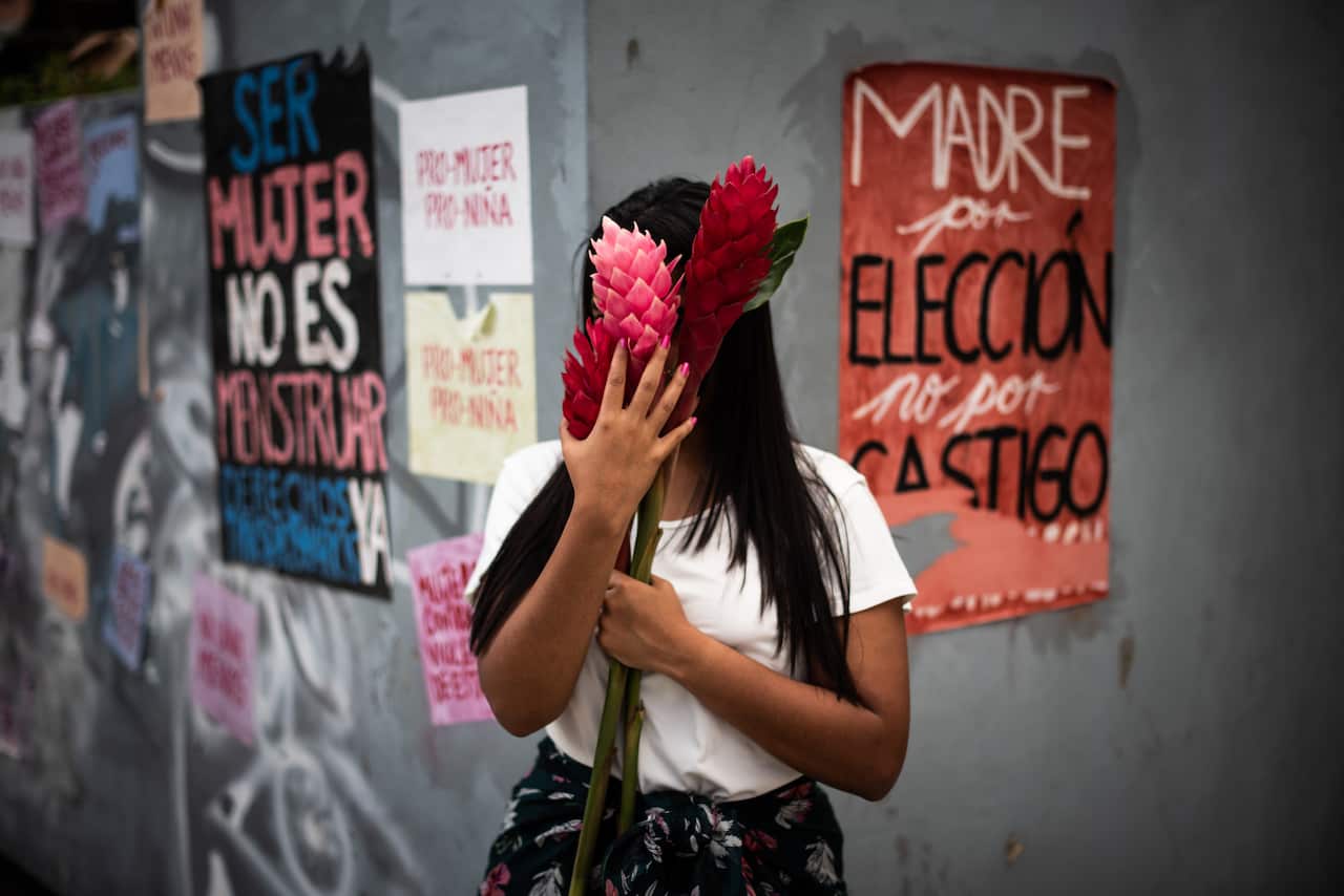 Jessika, 21, who went through an abortion alone, in front of a street art installation made by feminist activists in Caracas, Venezuela, Dec. 11, 2020. (Meridith Kohut/The New York Times)
