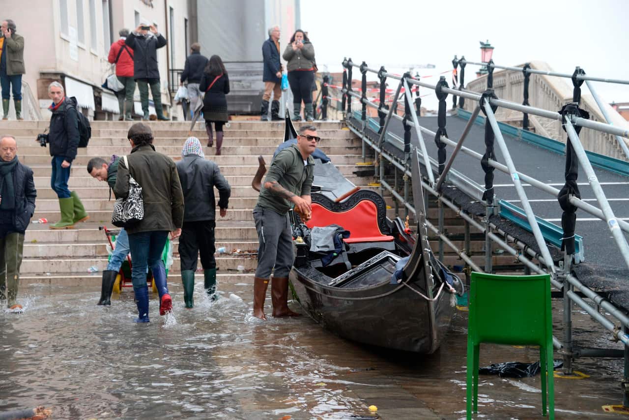 A man clean up a gondola boat after the high tide in Venice, Italy. The historic city’s mayor has blamed the high tide on climate change.