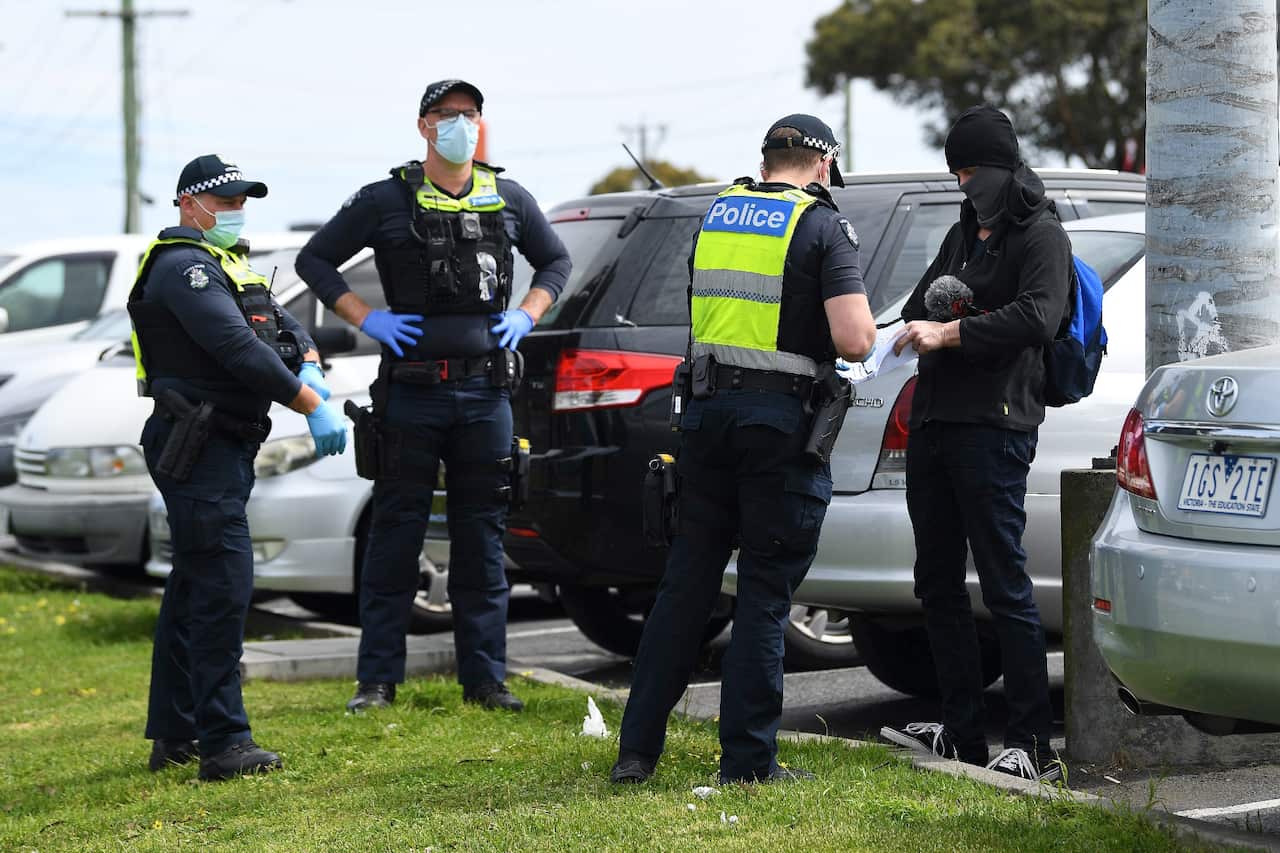 Victorian Police officers speak to protesters at a rally near Campbellfield Plaza in Melbourne.