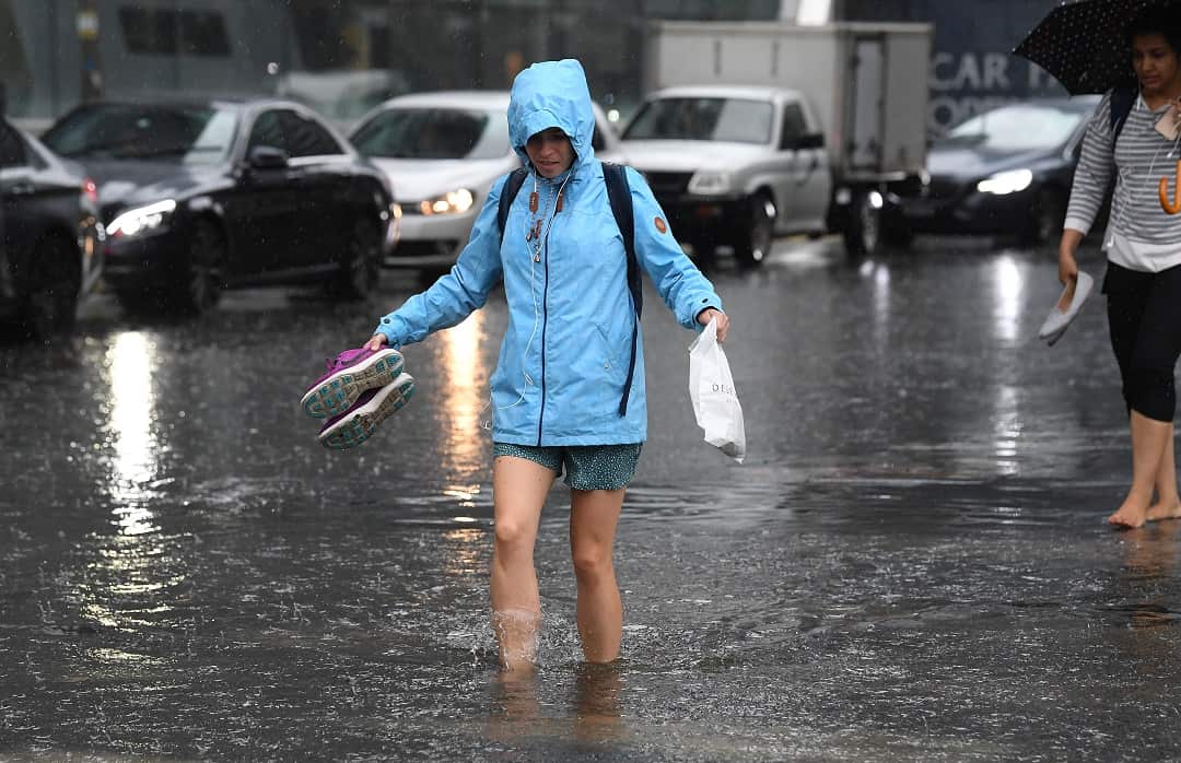 Pedestrians walk through flood waters at the corner of Clarendon and Cecil Street in South Melbourne. 
