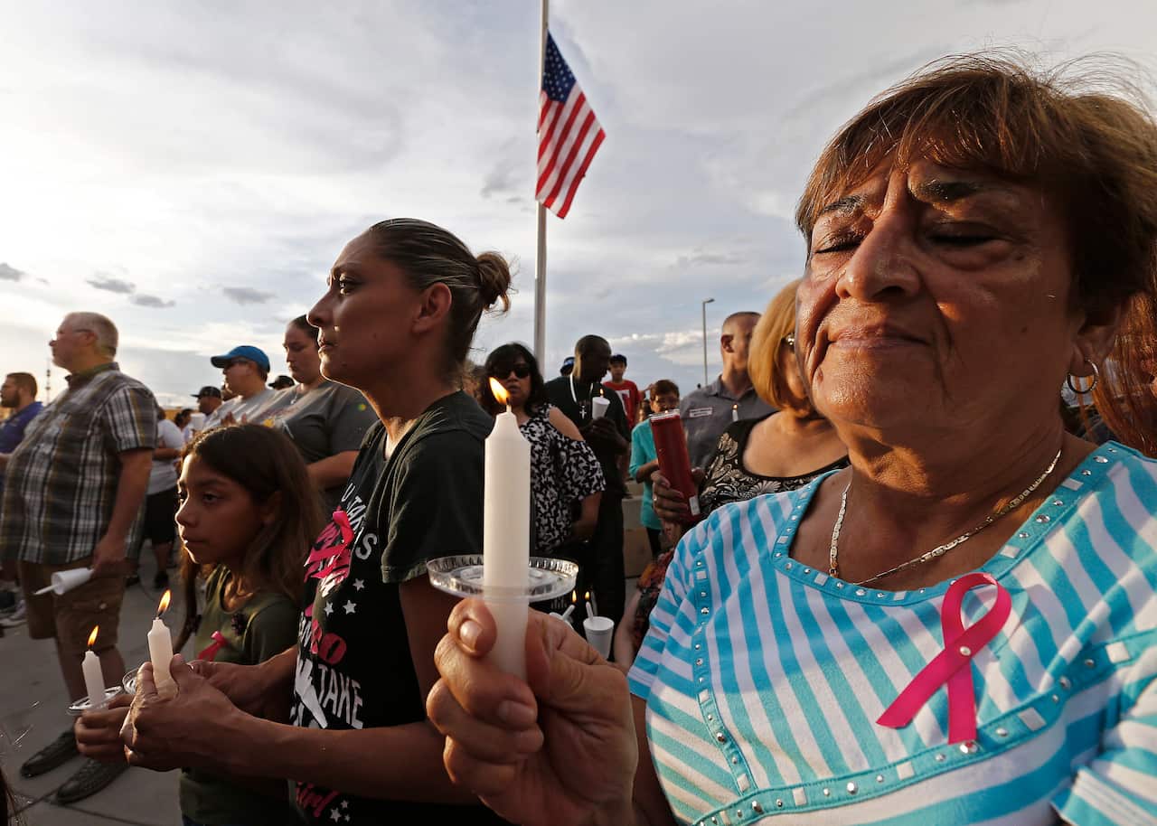 People hold candles at a vigil for the victims of the El Paso shooting. 