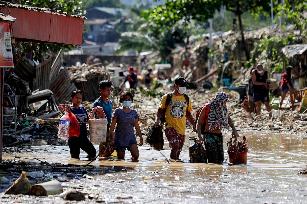 Residents walk on mud and debris as they retrieve belongings from their homes at the typhoon-damaged Kasiglahan village in Rizal province, Philippines.