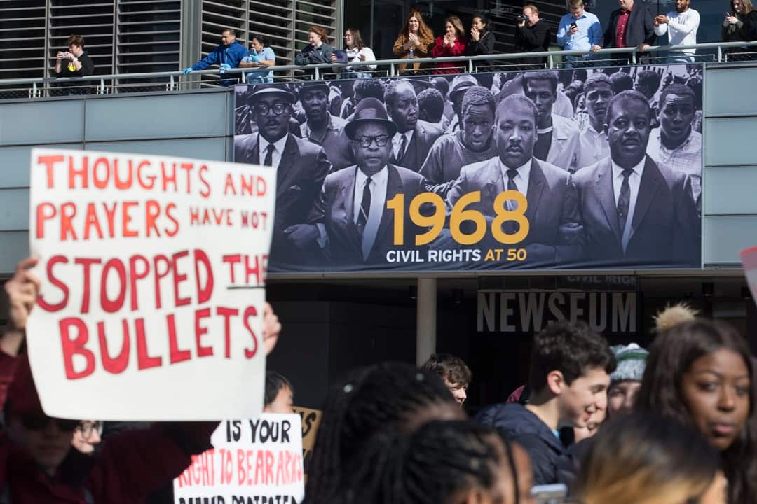 Young people marching in the national school walkout over gun violence pass the image of the late Dr. Martin Luther King Jr., as people cheer them on at the Newseum while the group walks from the White House to Capitol Hill, in Washington, DC, 14 March.