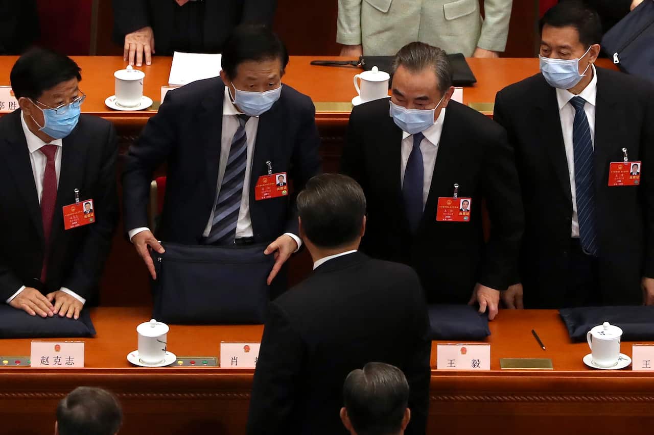 Chinese Foreign Minister Wang Yi, second from right, talks with Chinese President Xi Jinping, after the opening session of China's National People's Congress.